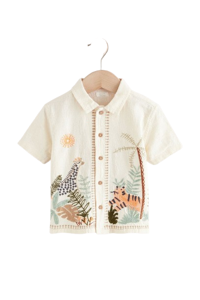 Children's white shirt with embroidered jungle animals hanging on wooden hanger.